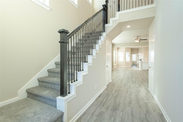 staircase featuring a high ceiling, hardwood / wood-style flooring, and ceiling fan