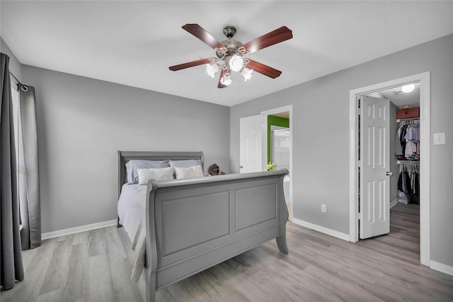 bedroom with ceiling fan, light hardwood / wood-style floors, and a spacious closet