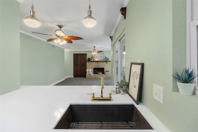 kitchen featuring pendant lighting, ceiling fan, crown molding, and sink