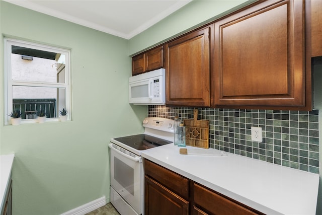 kitchen with white appliances, crown molding, and tasteful backsplash