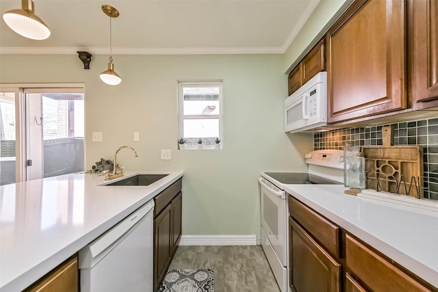 kitchen with white appliances, backsplash, light countertops, and a sink