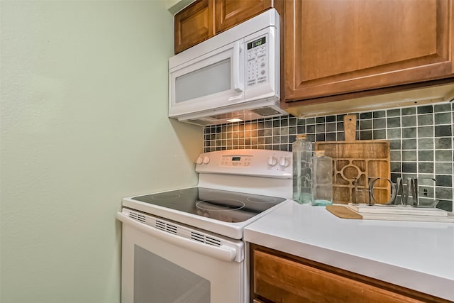 kitchen with white appliances, tasteful backsplash, brown cabinets, and light countertops