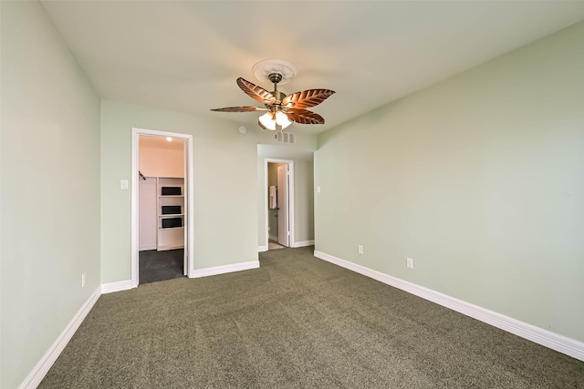 empty room with dark carpet, a ceiling fan, baseboards, and visible vents