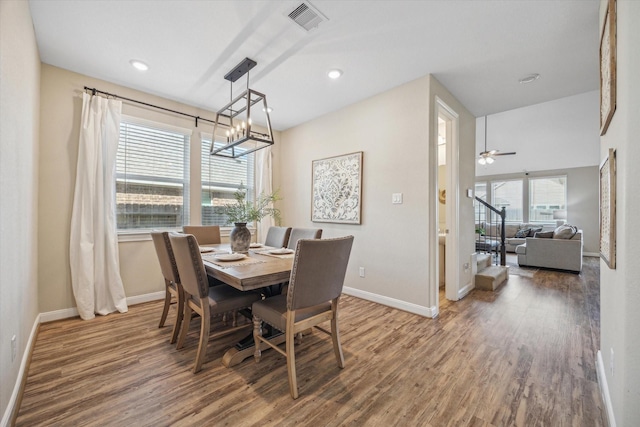 dining space featuring ceiling fan with notable chandelier, wood-type flooring, and a wealth of natural light