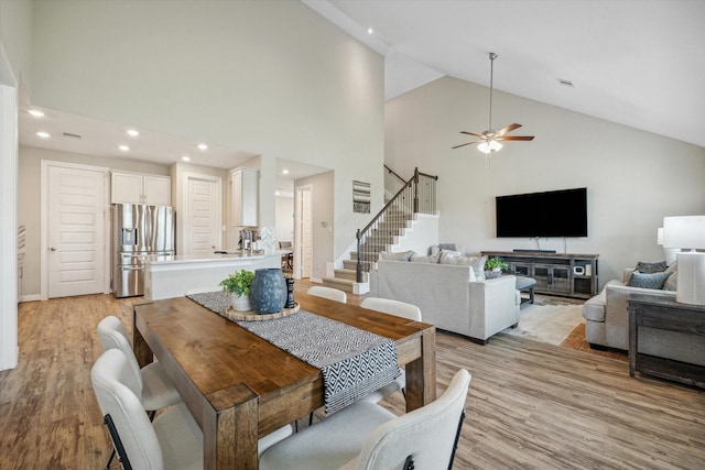 dining space with light hardwood / wood-style floors, high vaulted ceiling, and ceiling fan