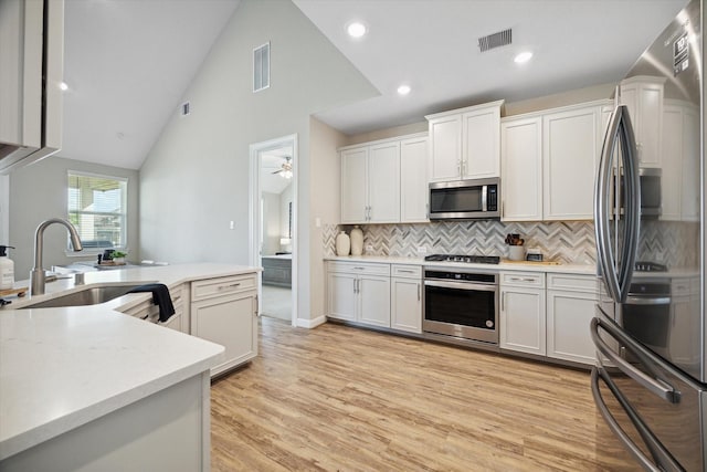 kitchen with white cabinets, decorative backsplash, sink, and stainless steel appliances