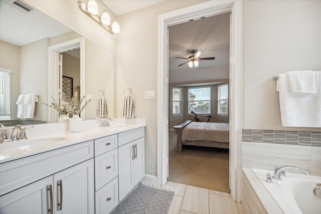 bathroom with tile patterned flooring, vanity, ceiling fan, and tiled bath