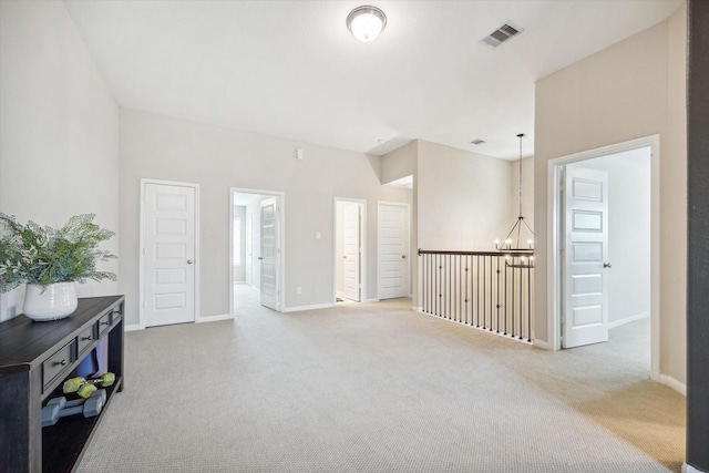 carpeted empty room featuring an inviting chandelier