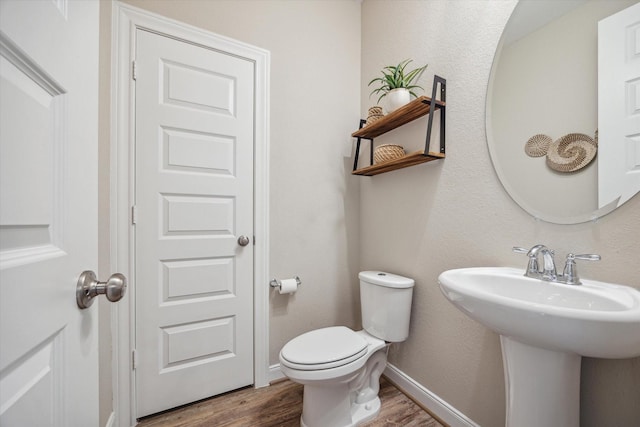 bathroom with hardwood / wood-style flooring, toilet, and sink