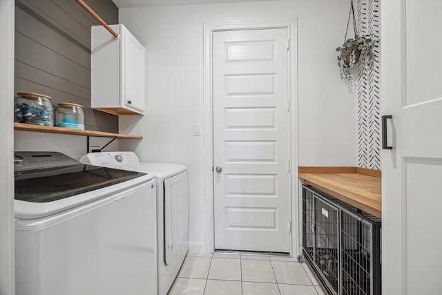 laundry area with cabinets, light tile patterned floors, and washing machine and clothes dryer