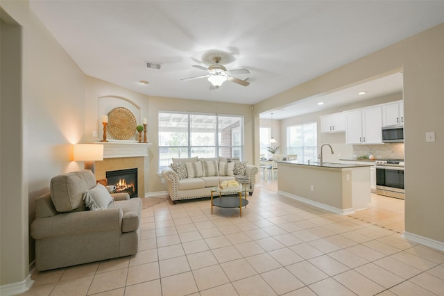 tiled living room featuring a tile fireplace, ceiling fan, and sink