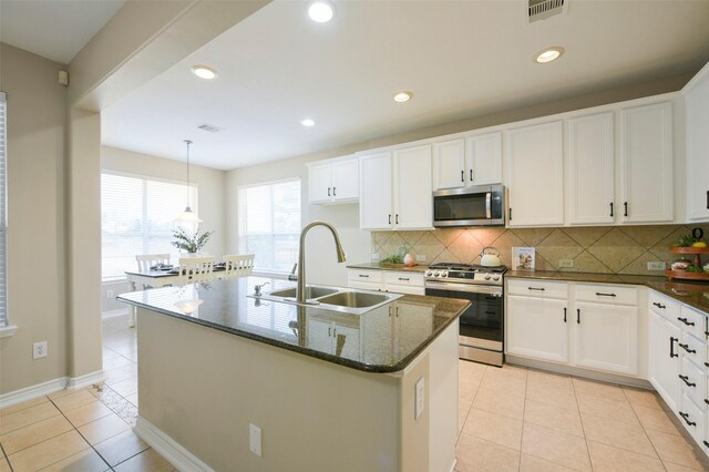 kitchen featuring sink, stainless steel appliances, tasteful backsplash, a center island with sink, and light tile patterned floors