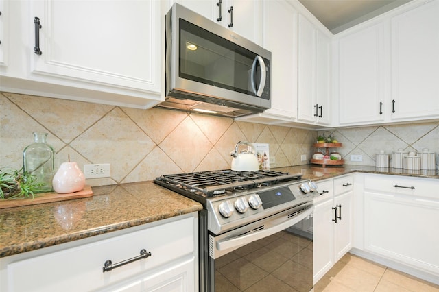 kitchen featuring white cabinets, dark stone counters, appliances with stainless steel finishes, and tasteful backsplash