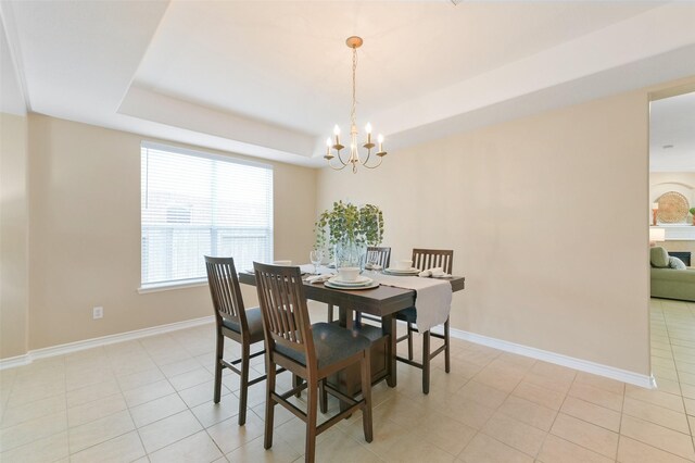 dining space with a tray ceiling, light tile patterned floors, and a chandelier