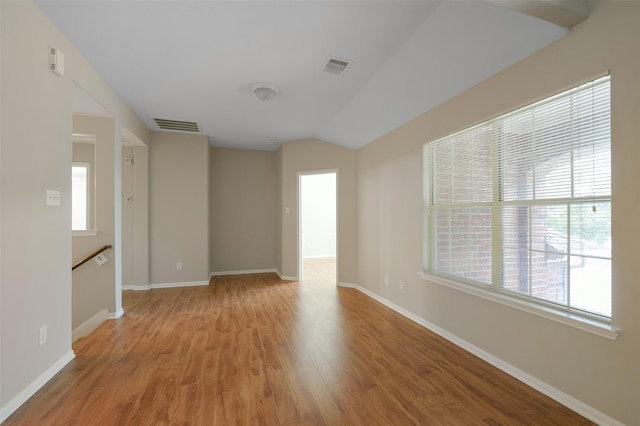 empty room with light hardwood / wood-style floors and lofted ceiling