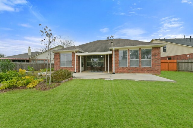 back of property featuring a sunroom, a patio area, and a lawn