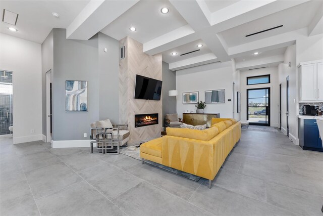 living room with beam ceiling, a towering ceiling, coffered ceiling, and a premium fireplace