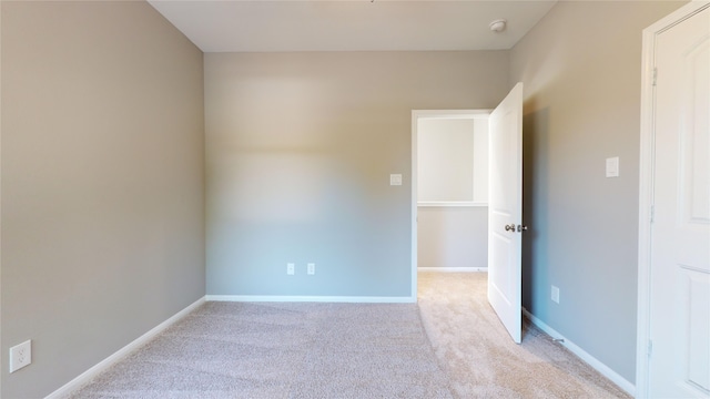 spare room with light colored carpet and baseboards