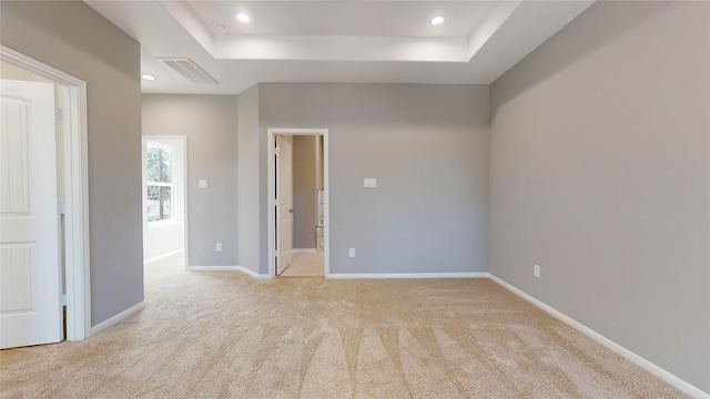 unfurnished room featuring light carpet, visible vents, baseboards, and a tray ceiling