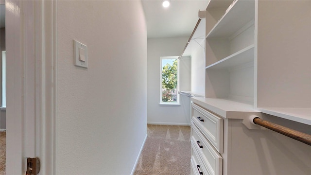 spacious closet with light carpet and built in desk