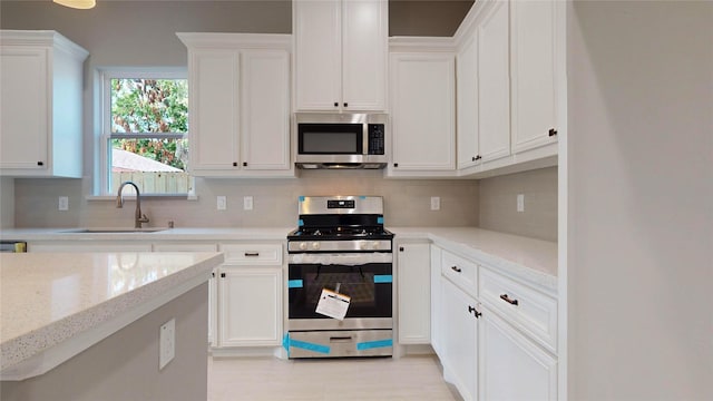 kitchen featuring light stone counters, sink, white cabinets, and stainless steel appliances