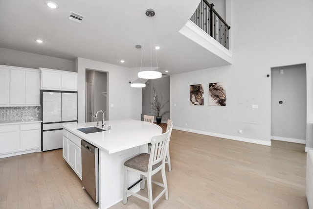 kitchen featuring a kitchen island with sink, sink, white cabinets, and stainless steel dishwasher