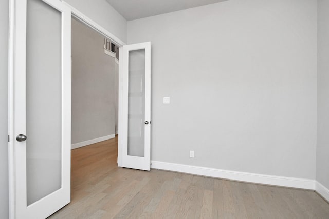 spare room featuring light hardwood / wood-style flooring and french doors