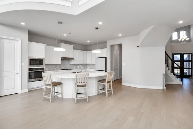 kitchen featuring stainless steel oven, white cabinets, white refrigerator, built in microwave, and tasteful backsplash