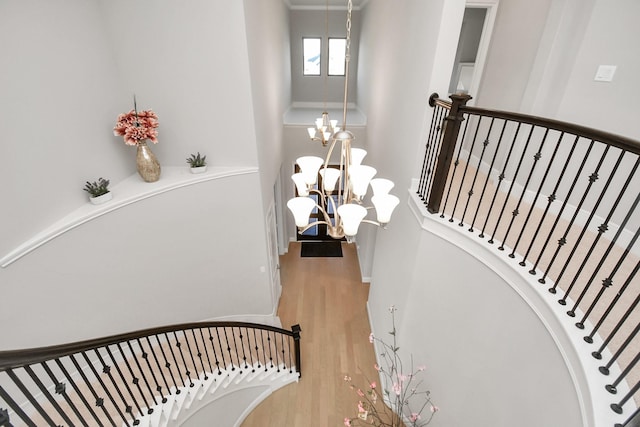 stairway with hardwood / wood-style flooring and an inviting chandelier