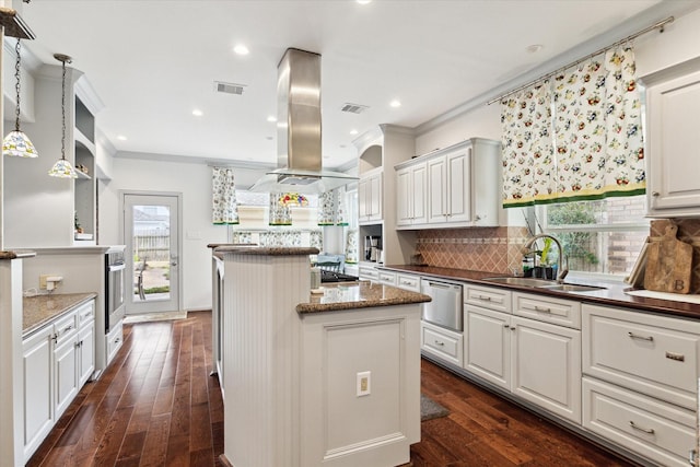 kitchen featuring dark stone countertops, pendant lighting, sink, white cabinetry, and island range hood