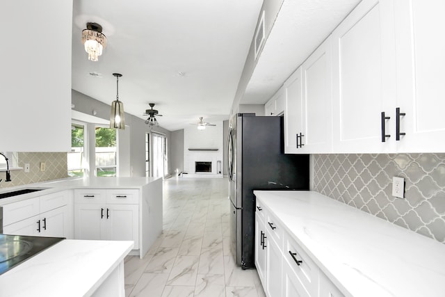 kitchen with ceiling fan, tasteful backsplash, white cabinetry, and a brick fireplace