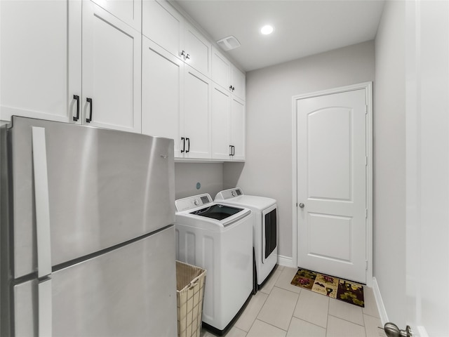 laundry area with washing machine and dryer, light tile patterned floors, and cabinets