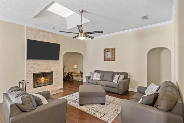 living room with ceiling fan, a fireplace, crown molding, and a textured ceiling