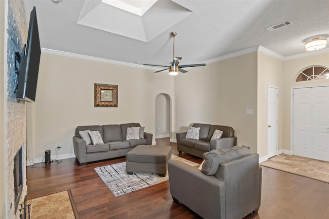 living room with a textured ceiling, ceiling fan, crown molding, and dark wood-type flooring