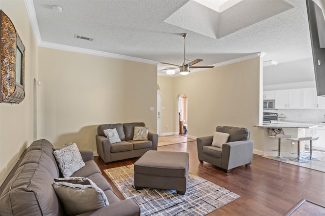 living room featuring ceiling fan, hardwood / wood-style floors, a textured ceiling, and ornamental molding