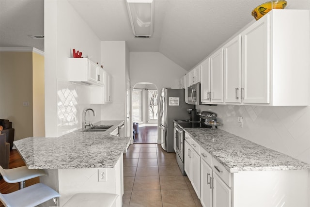 kitchen featuring white cabinets, a kitchen breakfast bar, sink, appliances with stainless steel finishes, and kitchen peninsula