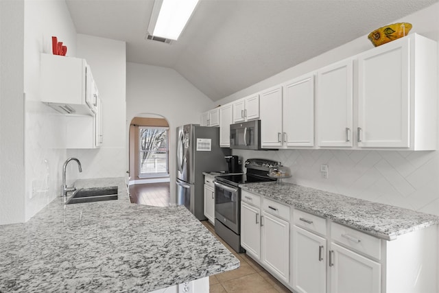 kitchen featuring decorative backsplash, appliances with stainless steel finishes, sink, white cabinetry, and lofted ceiling