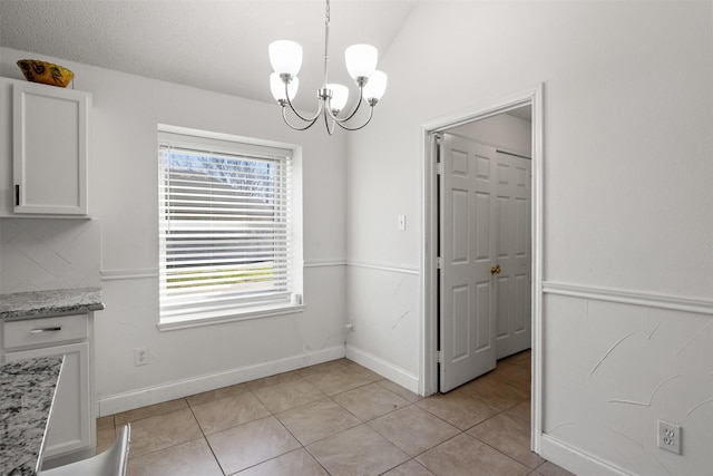 unfurnished dining area featuring light tile patterned flooring, lofted ceiling, and a notable chandelier