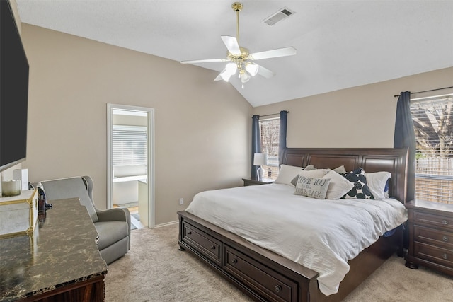 bedroom featuring light carpet, ensuite bath, ceiling fan, and lofted ceiling