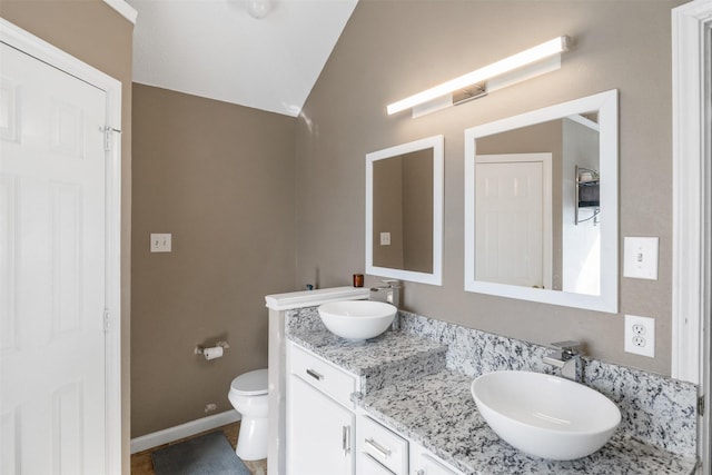 bathroom featuring vanity, toilet, and lofted ceiling