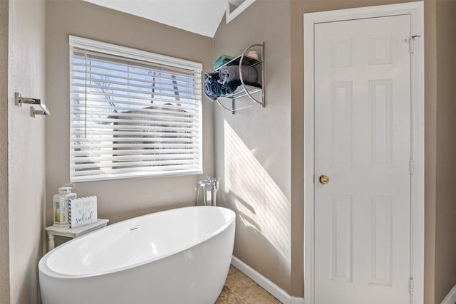 bathroom with a washtub, tile patterned floors, and lofted ceiling