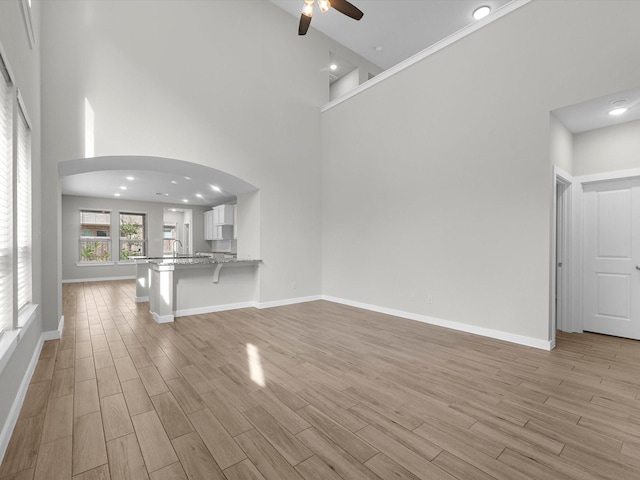 unfurnished living room featuring ceiling fan, sink, and a towering ceiling