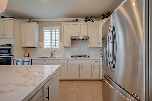 kitchen featuring light stone countertops, appliances with stainless steel finishes, backsplash, sink, and light tile patterned flooring