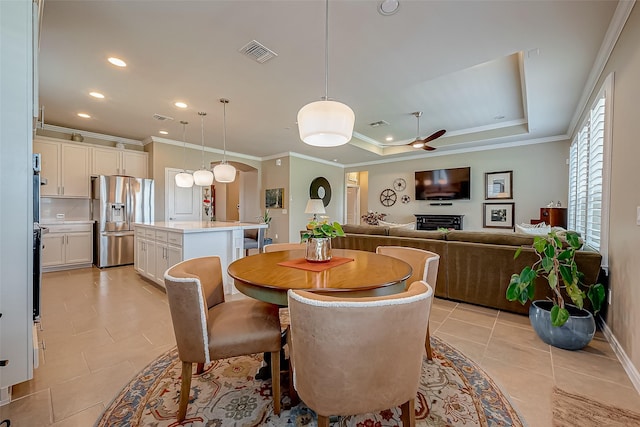 tiled dining room featuring ceiling fan, a raised ceiling, and crown molding