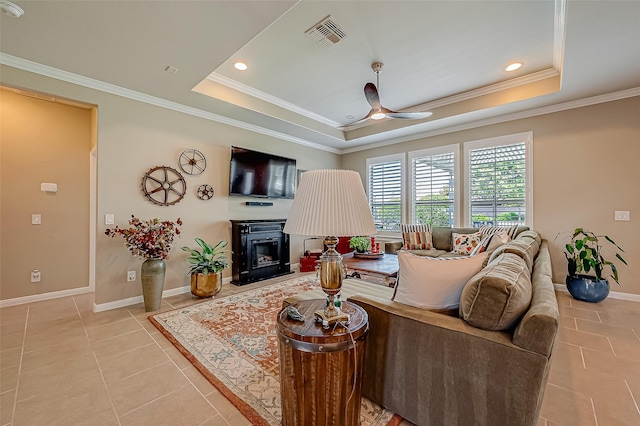 tiled living room featuring a raised ceiling, ceiling fan, and crown molding