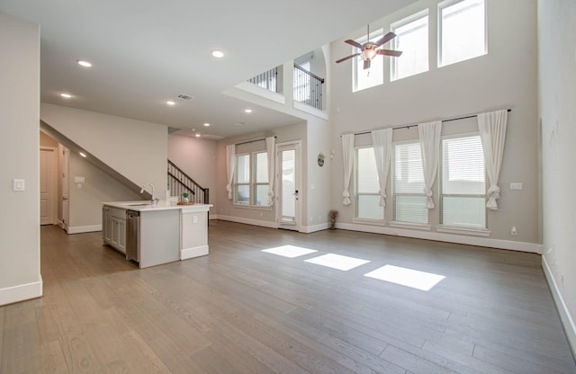 unfurnished living room with light hardwood / wood-style floors, plenty of natural light, ceiling fan, and sink