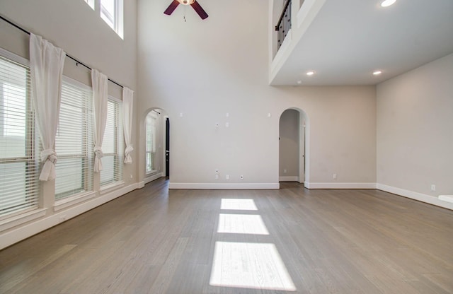 unfurnished living room featuring a high ceiling, light hardwood / wood-style floors, and ceiling fan