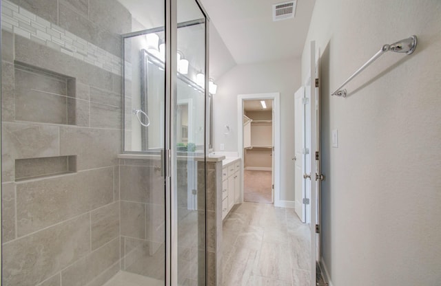 bathroom with vanity, vaulted ceiling, and walk in shower