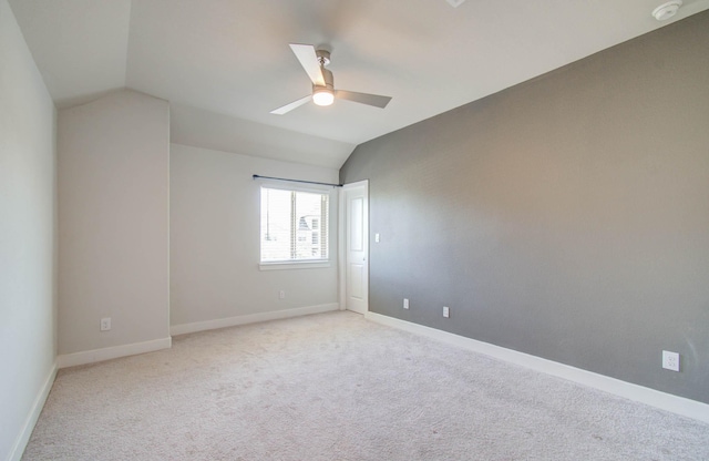 carpeted spare room with ceiling fan and vaulted ceiling