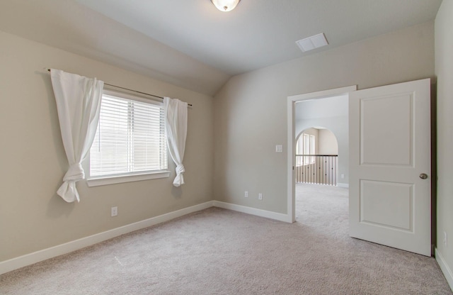 carpeted empty room featuring vaulted ceiling